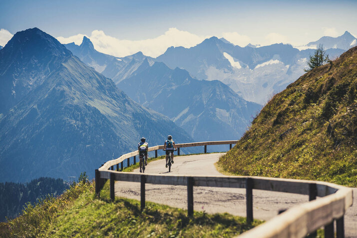 Zwei Radfahrer fahren vor einer traumhaften Bergkulisse
