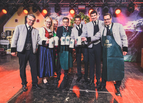 Männer und Frauen in Trachtkleidung mit Bierkrügen in der Hand 