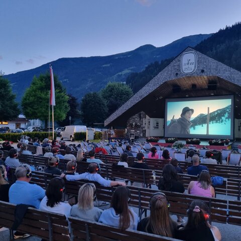 Sommerkino in Zell am Ziller am Musikpavillon, mit einem Film und einer Gruppe von Menschen auf Bänken