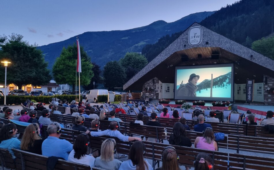 Sommerkino in Zell am Ziller am Musikpavillon, mit einem Film und einer Gruppe von Menschen auf Bänken