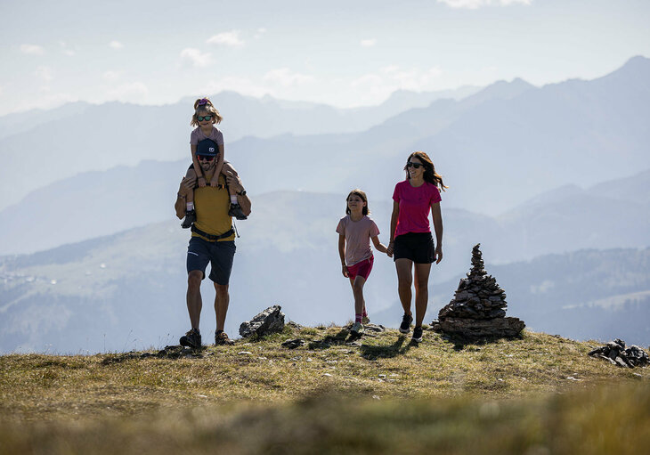 Ein Mann trägt ein kleines Mädchen auf seinen Schultern und eine Frau hält ein anderes Mädchen an der Hand