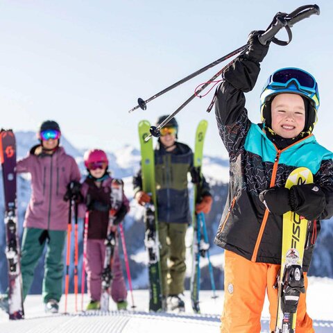 Eine Frau, ein Mann und zwei Kinder stehen auf der Piste auf ihren Skiern