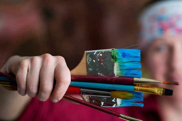 Eine Person hält mehrere verschiedene Pinsel in der Hand 