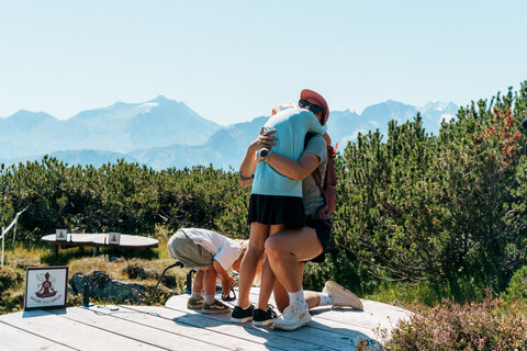 Eine Familie umarmt sich auf einer Yoga-Plattform.