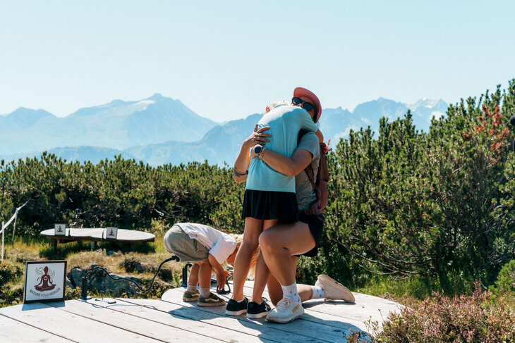 Eine Familie umarmt sich auf einer Yoga-Plattform.