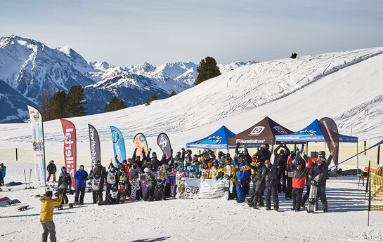 Eine Gruppe Snowboarder stehen am Rand einer Piste.