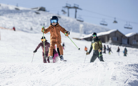 Ein kleiner Junge rast auf Skiern über die Piste