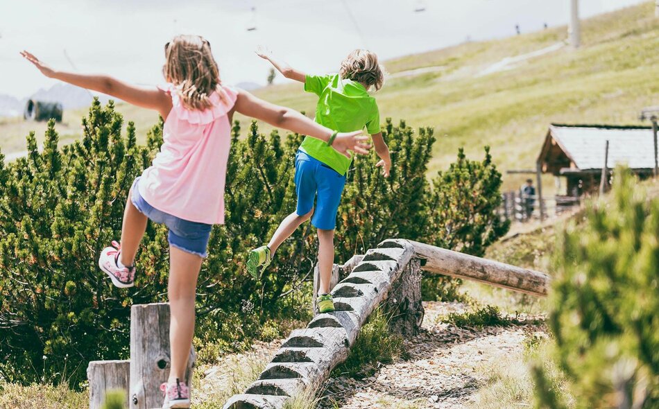 Ein Junge und ein Mädchen balancieren auf einem Holzstamm
