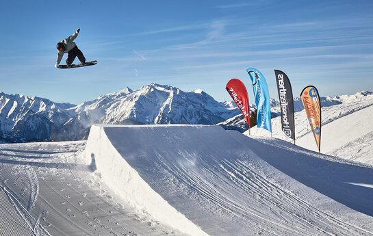 Eine Snowboarder springt über eine Rampe.