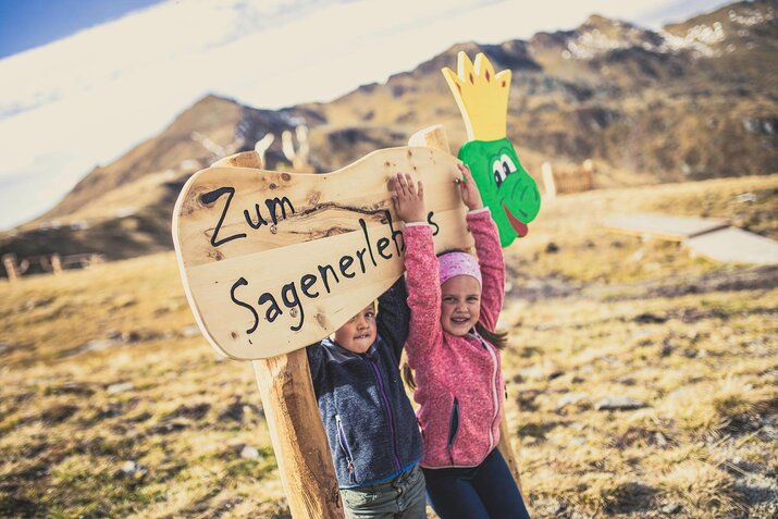 Zwei Kinder stehen an einem Holzschild