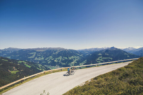 Zwei Radfahrer fahren vor einer traumhaften Bergkulisse