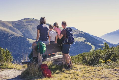 Eine Familie sitzt auf einer Bank und beobachtet eine traumhafte Bergkulisse