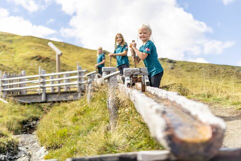 Kinder spielen an einem Wasserspielplatz.