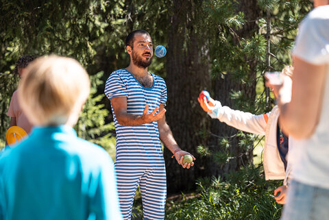 Ein Jongleure jongliert vor Kindern
