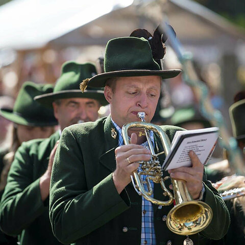 Ein in grüner Tracht gekleideter Trompetenspieler