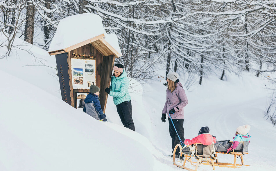 Zwei Frauen und drei Kinder stehen vor einer Infotafel