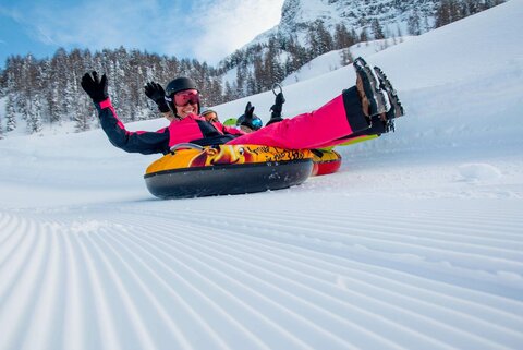 Zwei Personen fahren auf luftgefüllten Reifen die Piste hinunter