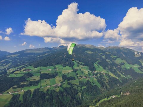 Ein Paragleiter fliegt bei traumhaften Wetter.