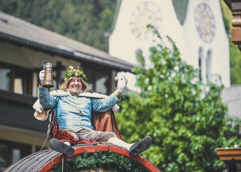 Ein verkleideter Mann mit Blumenkrone beim Gauder Fest