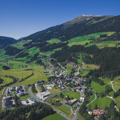 Blick auf eine Ortschaft umgeben von grüner Landschaft.