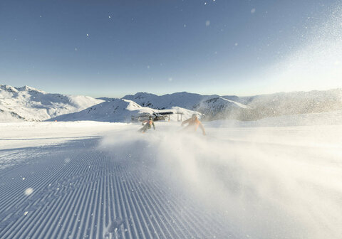 Zwei Skifahrer rasen den Berg hinunter.