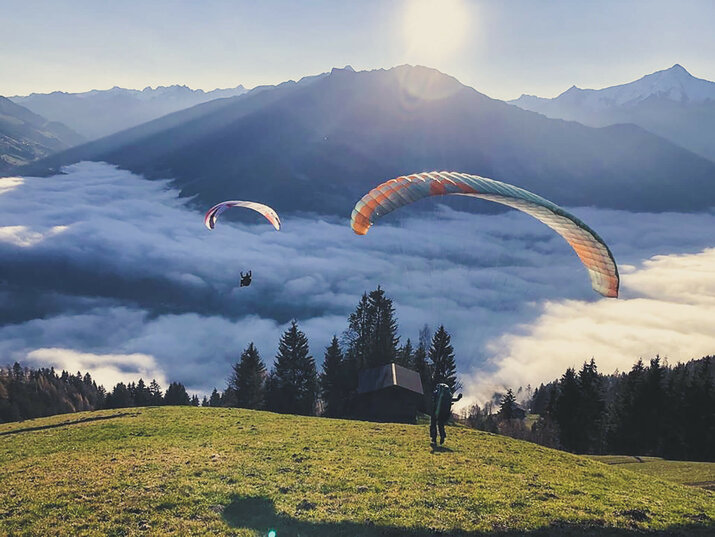 Paragleiter über den Wolken bei Sonnenaufgang