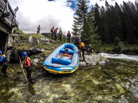 Teilnehmer setzen ein Rafting-Boot ins Wasser.