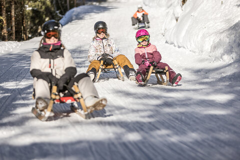 Drei Rodler fahren die Strecke hinunter