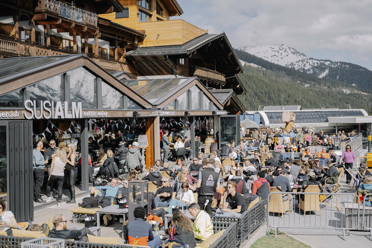 Menschen auf einer Sonnenterrasse im Hintergrund die Königsleiten Bergbahn