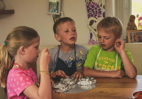 Drei Kinder sitzen an einem Esstisch