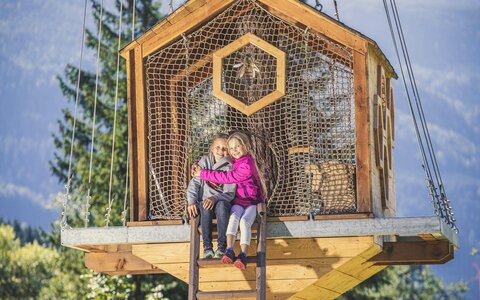 Zwei Mädchen sitzen auf einem Baumhaus