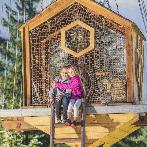 Zwei Mädchen sitzen auf einem Baumhaus