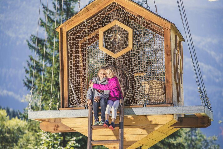 Zwei Mädchen sitzen auf einem Baumhaus