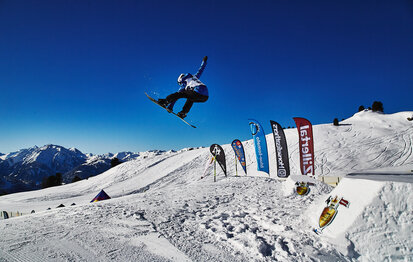 Ein Snowboarder springt über eine Rampe.