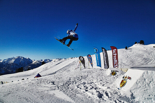 Ein Snowboarder springt über eine Rampe.