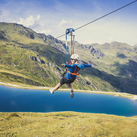 Eine Frau fährt mit einer Zipline über der traumhaften Natur