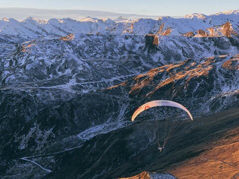 Ein Paragleiter fliegt über schneebedeckte Berge.