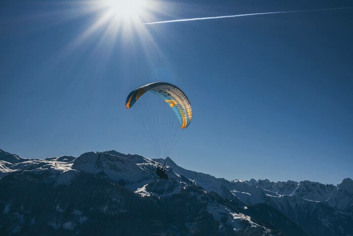 Ein Paragleiter zieht über die Gipfel der Berge