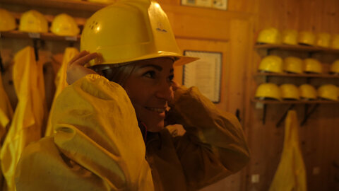 Eine Frau setzt sich einen gelben Schutzhelm auf