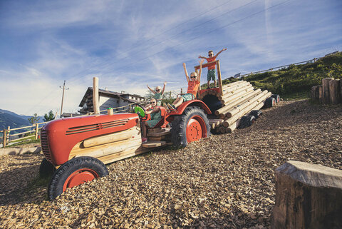 Kinder sitzen auf einem Traktor am Almspielplatz.