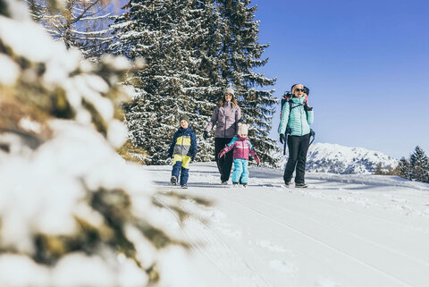 Zwei Frauen und drei Kinder spazieren durch den Schnee