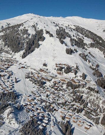 Blick auf ein schneebedecktes Dorf mit verschneiten Häusern und winterlichen Landschaften