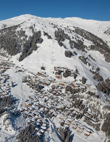 Blick auf ein schneebedecktes Dorf mit verschneiten Häusern und winterlichen Landschaften
