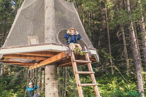 Ein Junge sitzt auf einem kleinen Baumhaus